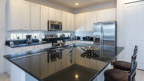 A modern kitchen with white cabinets, stainless steel appliances, and a central island. - Bella Vida 4507 (Kissimmee)
