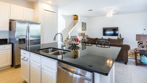 A modern kitchen with white cabinets, a stainless steel refrigerator, and a black countertop. - Bella Vida 4507 (Kissimmee)