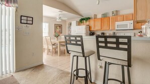 A kitchen with wooden cabinets, a white microwave, and a ceiling fan. - Silver Creek 17317 (Clermont)