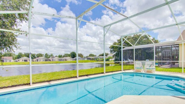 A pool with a clear view of houses and a body of water in the background. - Silver Creek 17317 (Clermont)