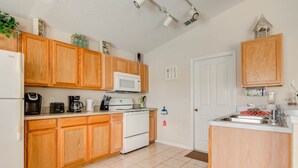 A compact kitchen with wooden cabinets, a microwave, a stove, and a sink. - Silver Creek 17317 (Clermont)