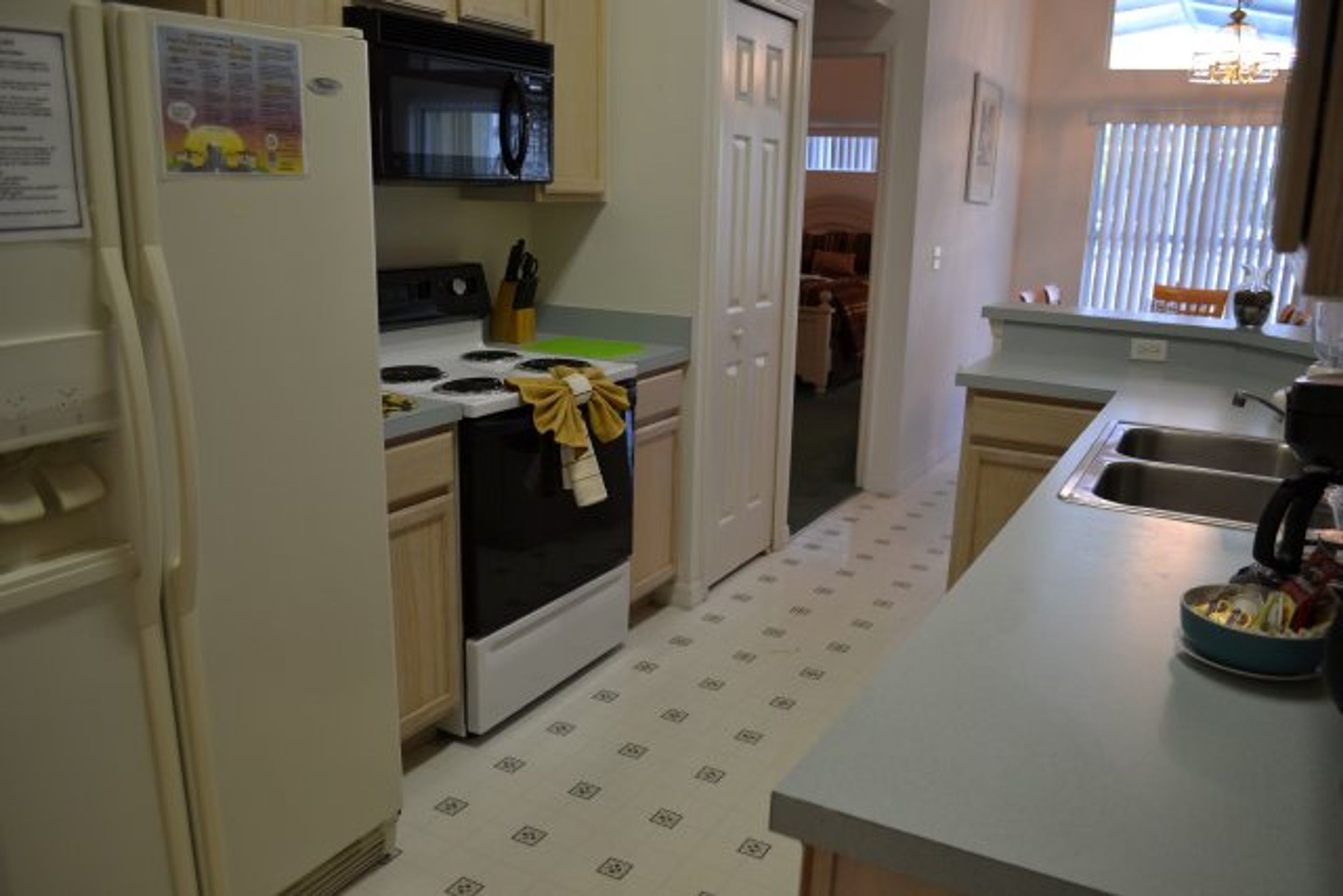 A compact kitchen with a refrigerator, stove, microwave, and sink.