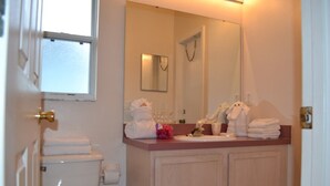 Une salle de bain équipée de toilettes, d’un lavabo, d’un miroir et de serviettes.