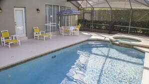 Ein Swimmingpool mit Liegestühlen und einer überdachten Terrasse.