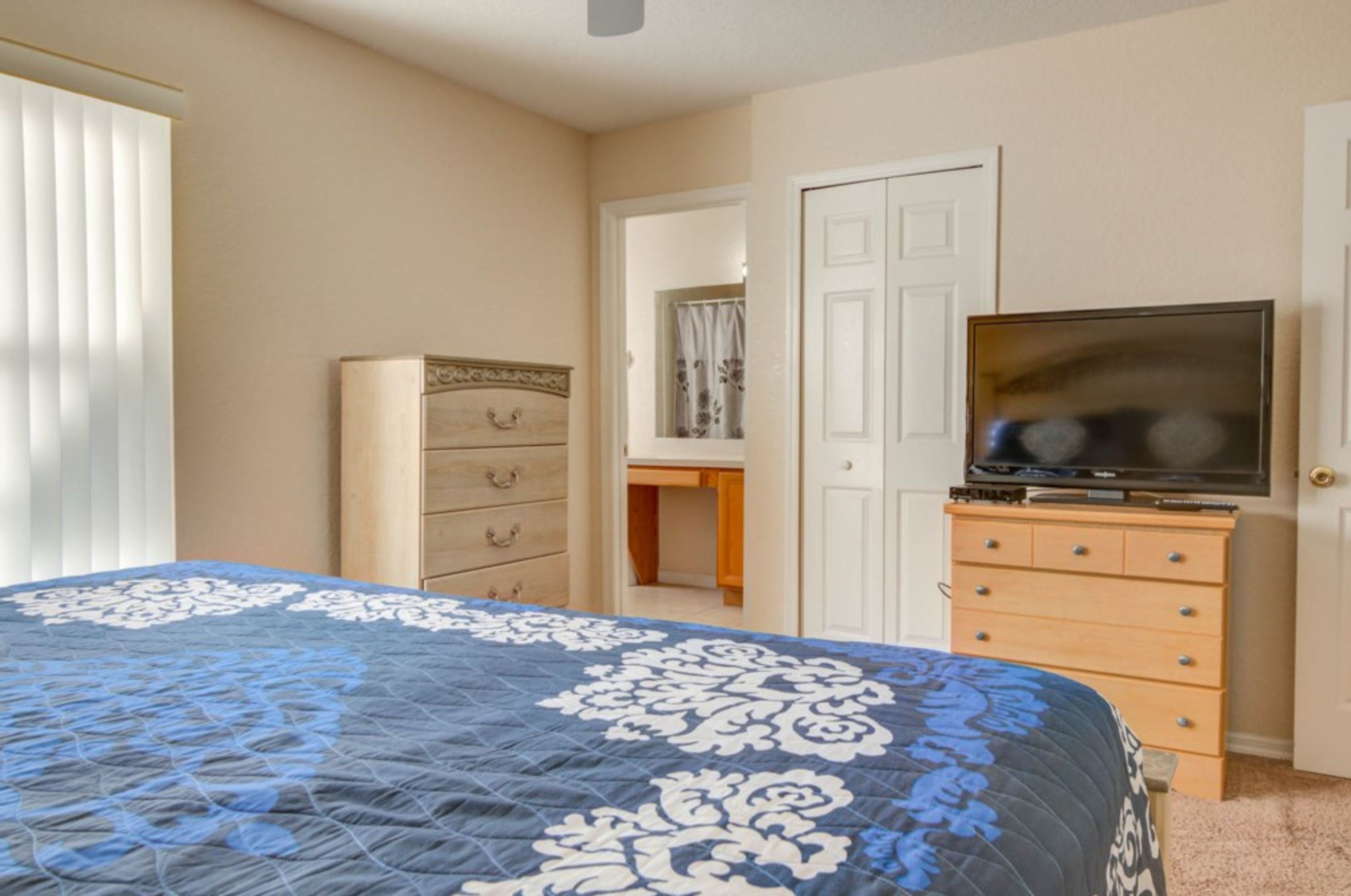 A bedroom with a bed, a dresser, a television, and a wardrobe.