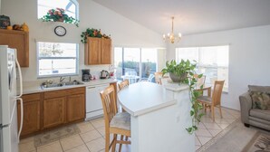 A kitchen with wooden cabinets, a white island, and a dining area with chairs.