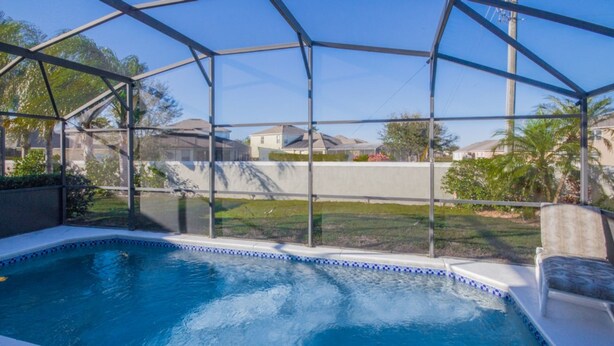 A swimming pool with a clear view of the surrounding neighborhood, including houses and greenery.