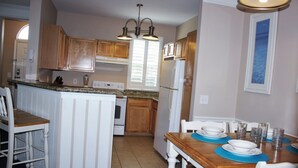 Una cocina con armarios de madera, un refrigerador blanco y una mesa de comedor con platos y vasos.