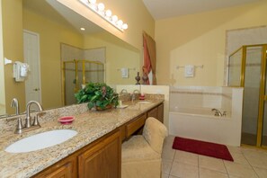 A bathroom with a large mirror, a sink, a bathtub, and a shower. - Formosa Gardens 2721 (Kissimmee)