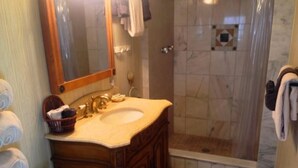 Une salle de bain avec un meuble-lavabo en bois, un évier et un espace douche.