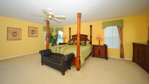 A bedroom with a four-poster bed, a ceiling fan, a nightstand, a lamp, and a dresser. - Legacy Park 120 (Davenport)