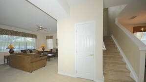 A living room with a sofa, a coffee table, and a lamp. There is a white door and a staircase leading to another level. - Legacy Park 120 (Davenport)