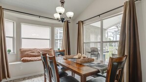 Un coin repas avec une table en bois, des chaises noires et un lustre.