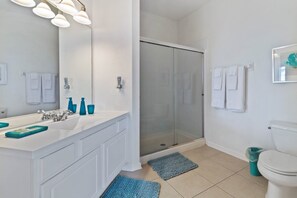 A modern bathroom with a white vanity, a glass shower enclosure, and a toilet. - Vista Cay 4862 - 202 (Orlando)