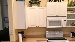 A kitchen with white cabinets, a microwave, an oven, and a sink. - Tuscan Hills 220 (Davenport)