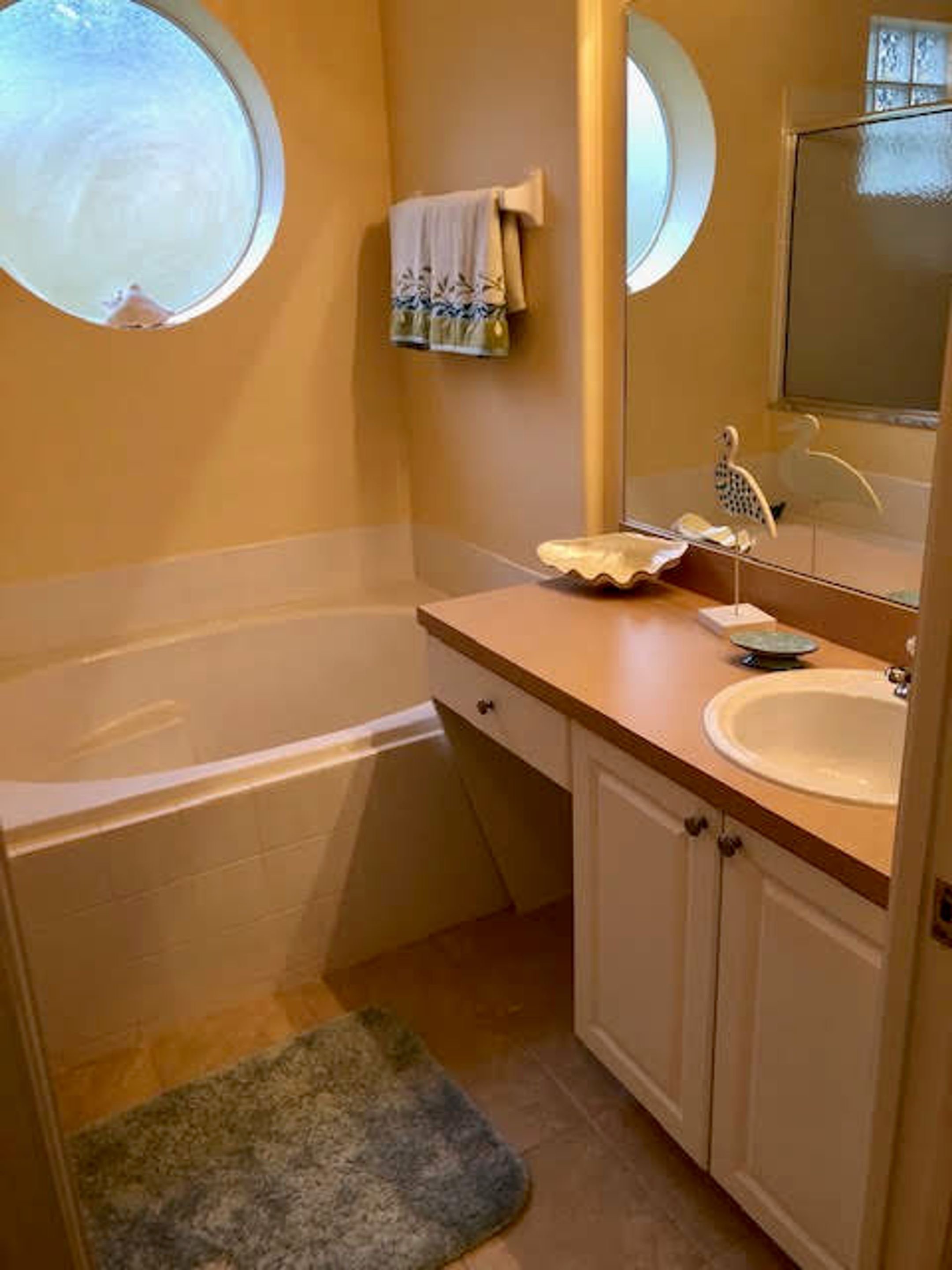 A bathroom with a bathtub, a sink, a mirror, and a towel rack.