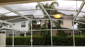A covered swimming pool with a glass roof, surrounded by greenery and a residential building in the background. - Tuscan Hills 220 (Davenport)