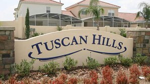 A sign for Tuscan Hills with a modern architectural style, featuring a curved roof and a stone facade. - Tuscan Hills 220 (Davenport)