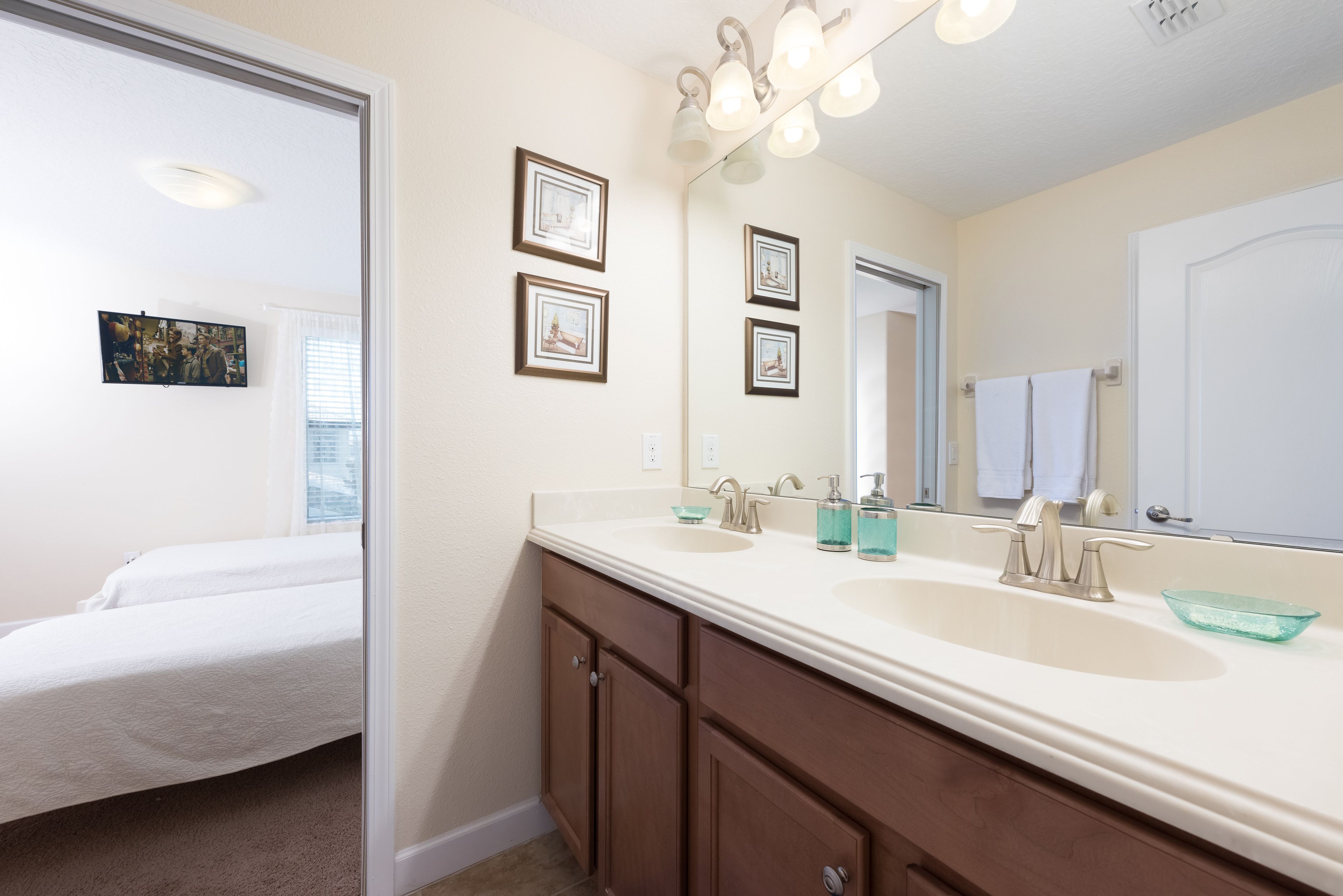 A bathroom with two sinks, a large mirror, and framed pictures on the wall.