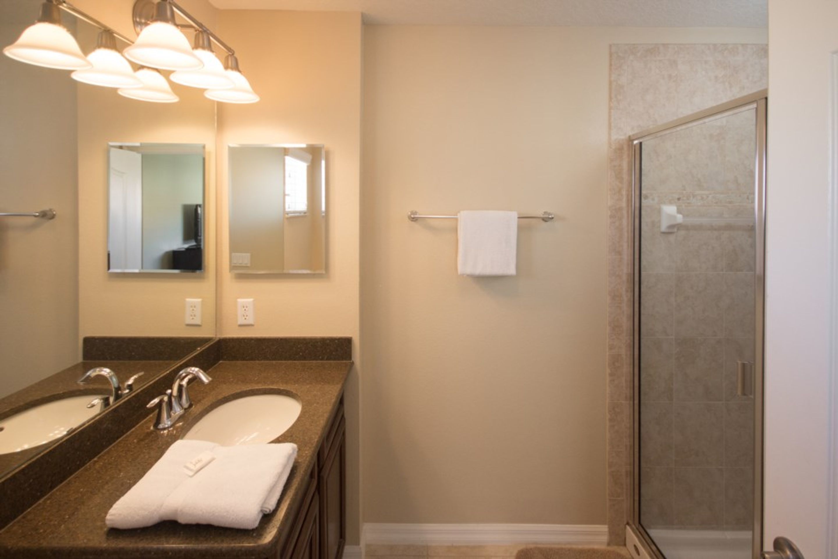 A bathroom with two sinks, a glass shower enclosure, and a towel rack.