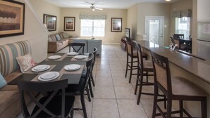 A spacious kitchen with a dining area, a sofa, and a staircase. - Paradise Palms 8964 (Kissimmee)