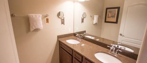 A bathroom with two sinks, a large mirror, and a towel rack.