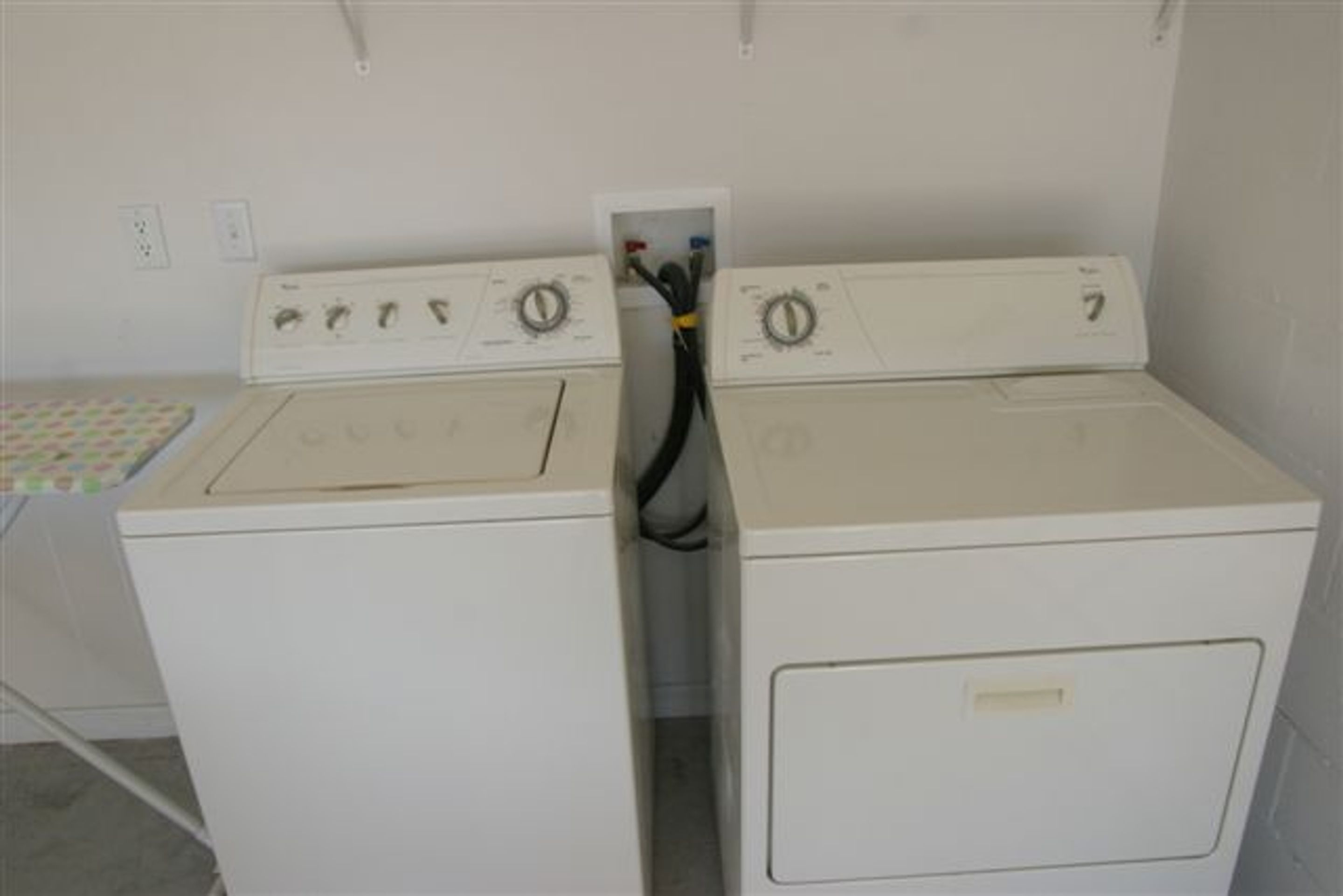 A laundry room with two stacked washers and dryers, a control panel with knobs and a power cord visible.
