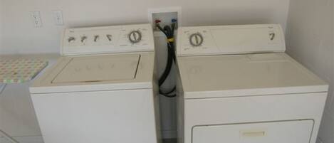 A laundry room with two stacked washers and dryers, a control panel with knobs and a power cord visible.