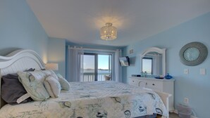 A bedroom with a bed, a dresser, a television, and a window with curtains.