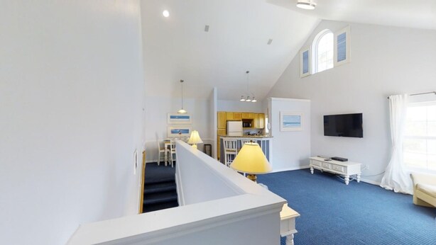 A spacious living area with a staircase, a kitchen, and a TV.