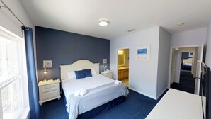 A hotel room with a large bed, bedside tables with lamps, a desk, and a view of the bathroom.