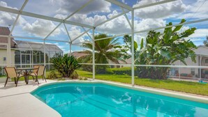 A swimming pool with a glass enclosure, surrounded by chairs and plants.