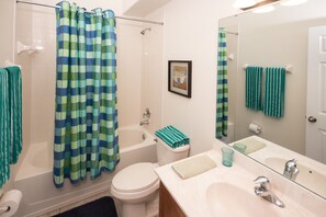 A bathroom with a bathtub, toilet, sink, and a shower curtain. - Veranda Palms 4458 (Kissimmee)