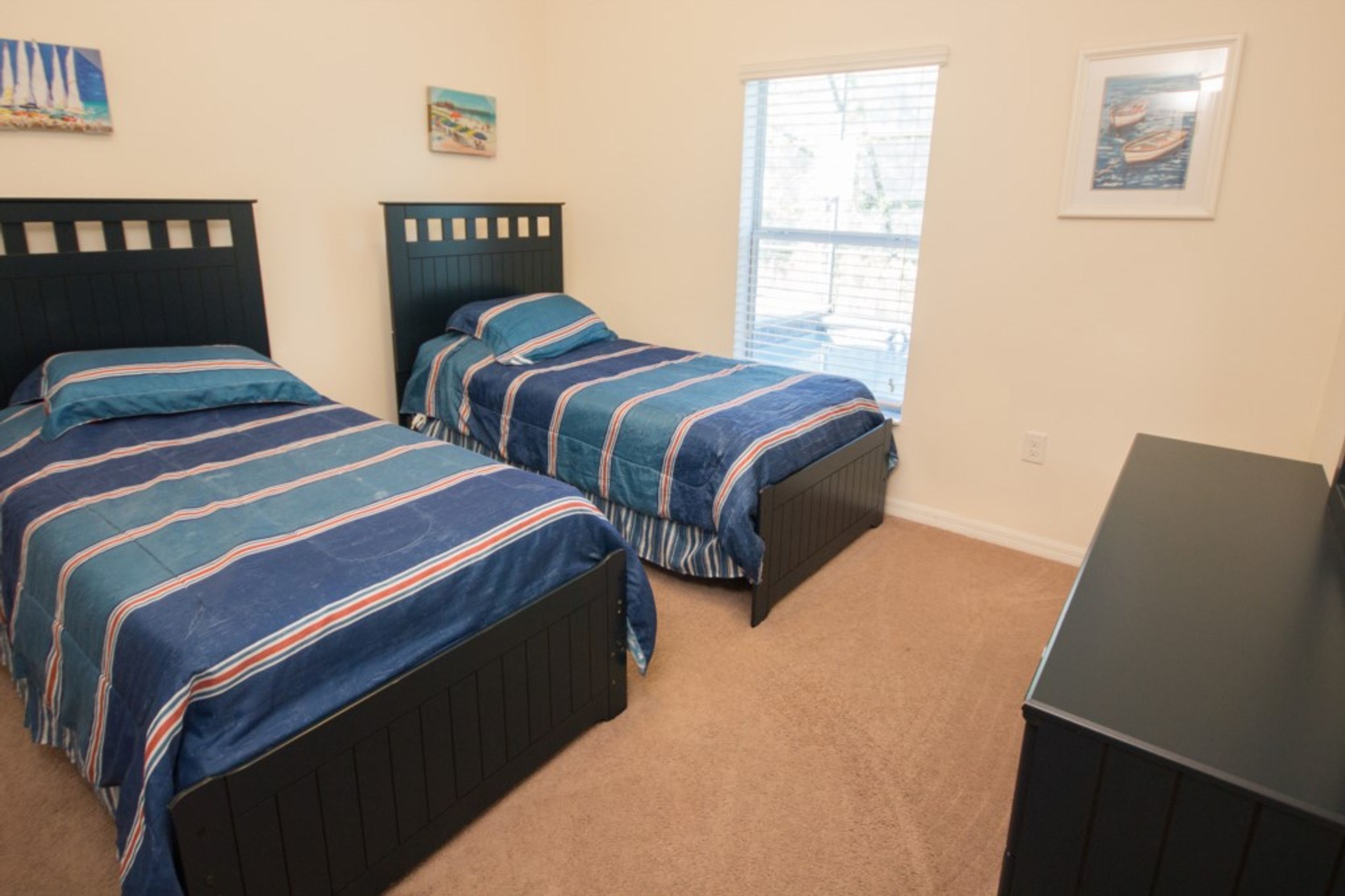 A bedroom with two beds, a window, and a desk.