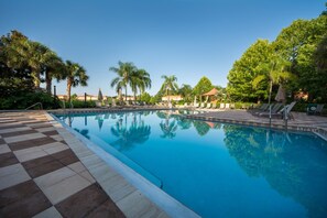 A swimming pool with clear blue water, surrounded by palm trees and lounge chairs. - Encantada Resort 3161 (Kissimmee)