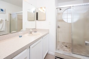 A modern bathroom with a large mirror, a sink, and a glass-enclosed shower.