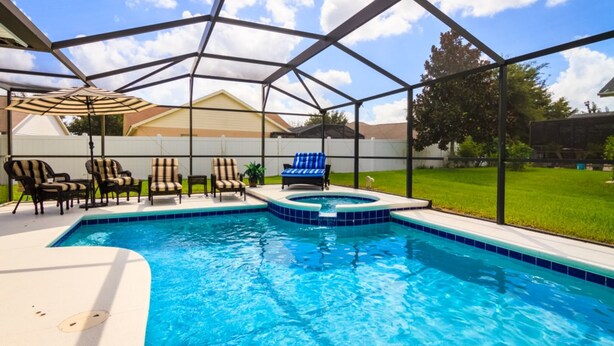 Una piscina nel giardino con idromassaggio, sedie a sdraio e una zona patio coperta.
