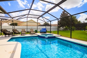A backyard swimming pool with a hot tub, lounge chairs, and a covered patio area. - Orange Tree 15915 (Clermont)