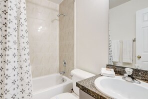 A bathroom with a bathtub, toilet, sink, and a mirror.
