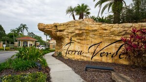 Un mur de pierres sur lequel est inscrit le texte « Terra Verde » et un chemin menant à un bâtiment.