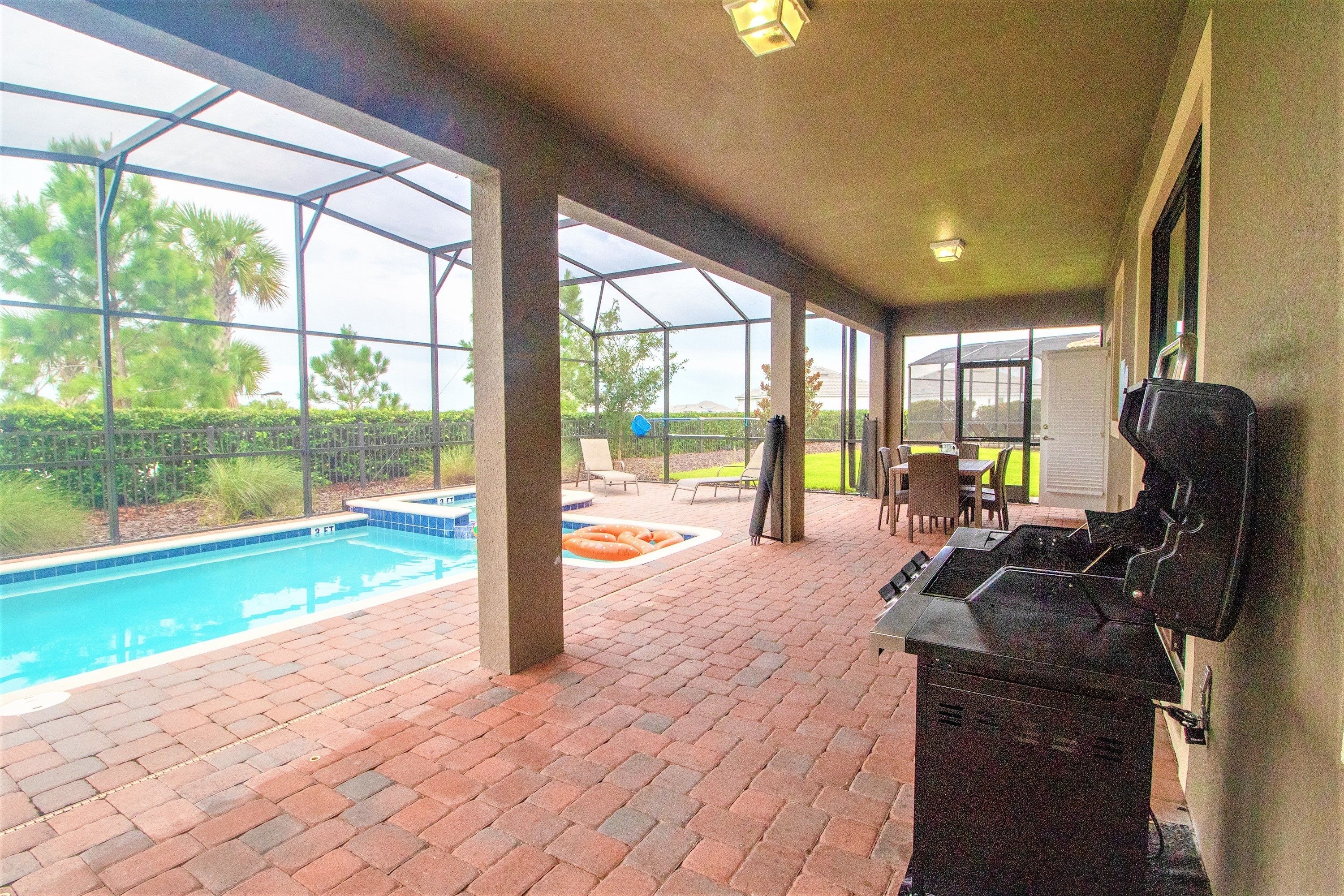 Une terrasse extérieure équipée d’un barbecue, d’une piscine et d’un espace salon abrité.
