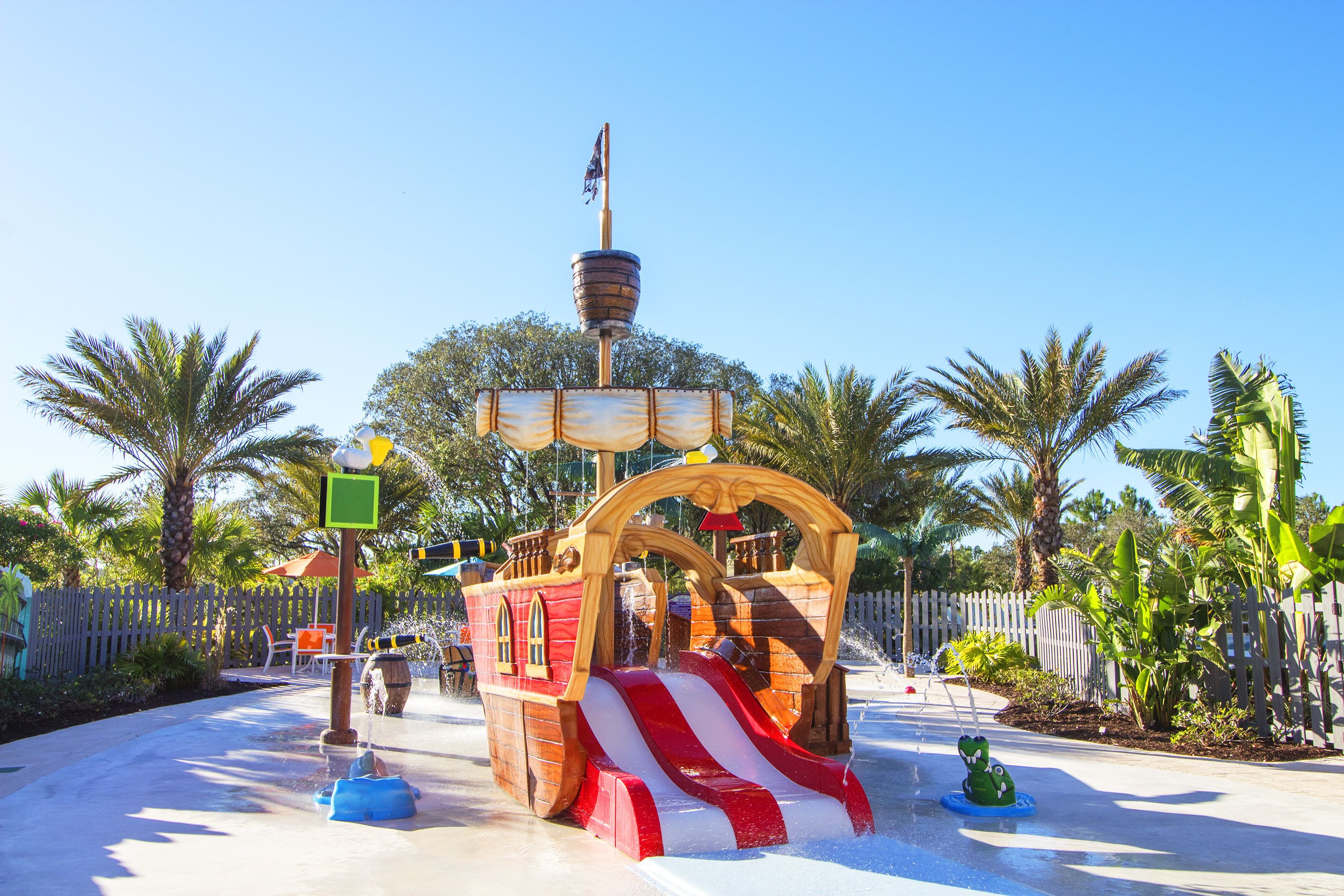 A pirate-themed water play area with a ship structure, slides, and a small boat.