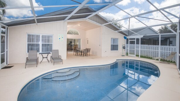 An indoor swimming pool with a covered patio area, including seating and a table.