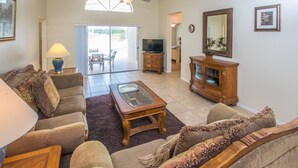 A living room with a sofa, a coffee table, a television, and a cabinet.