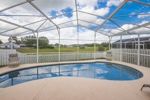 A covered swimming pool with a view of a grassy area and a white fence. - Indian Ridge Oaks 7709 (Kissimmee)