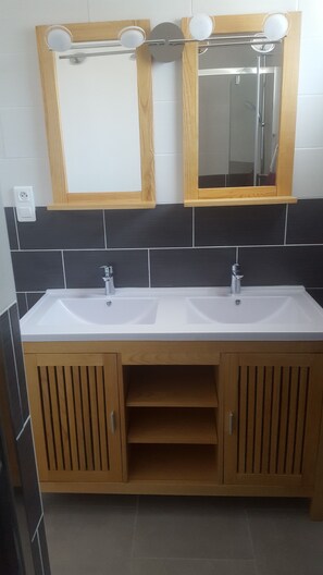 A bathroom with two sinks, wooden cabinets, and a mirror above the sinks.