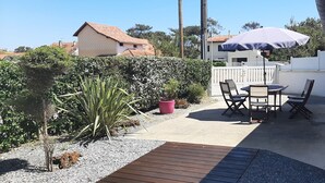 A patio with a table and chairs, a potted plant, and a wooden deck.