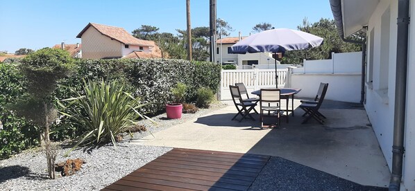 A patio with a table and chairs, a potted plant, and a wooden deck.