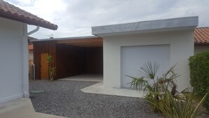 A modern house with a garage, gravel driveway, and potted plants.