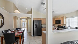 A modern kitchen with a central island, wooden cabinets, and a stainless steel refrigerator. - Rolling Hills 7979 (Kissimmee)